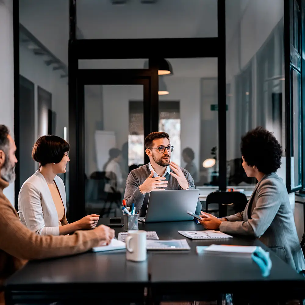 Team meeting in a modern office with professionals discussing a project around a table.